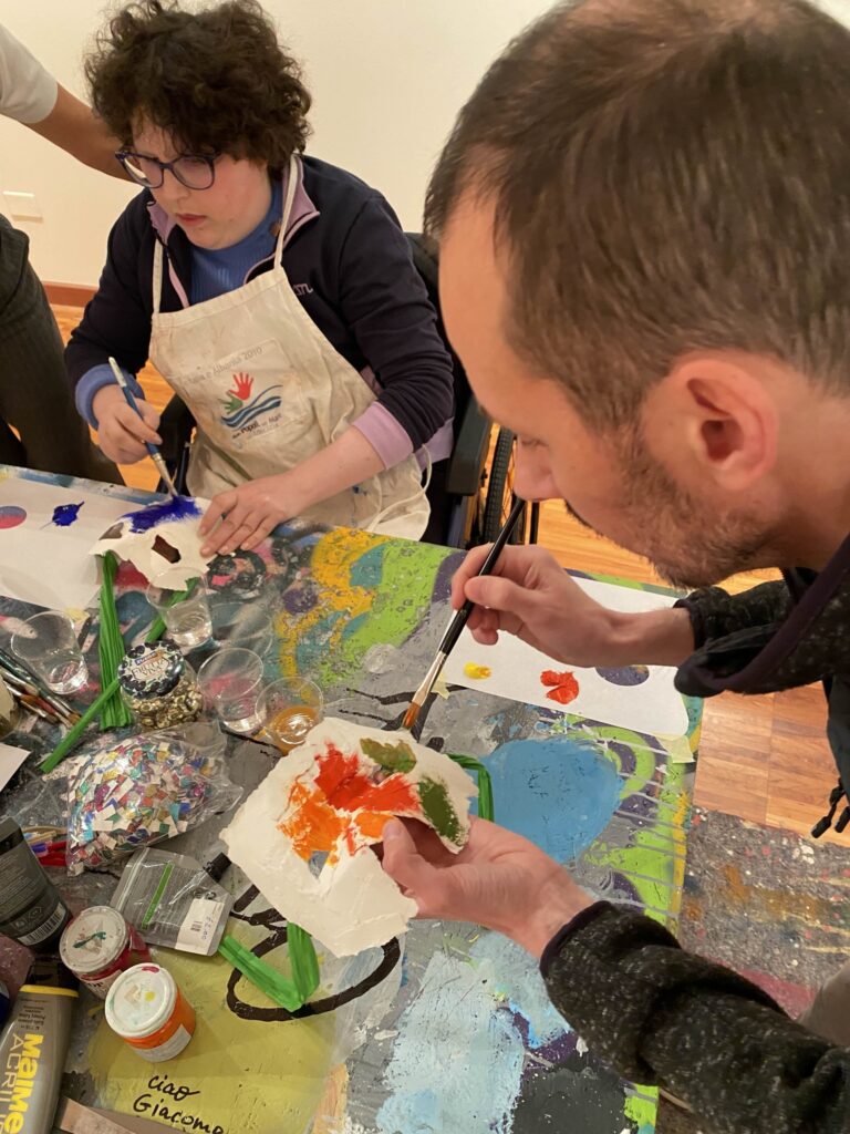 Due persone dipingono maschere durante un laboratorio artistico.