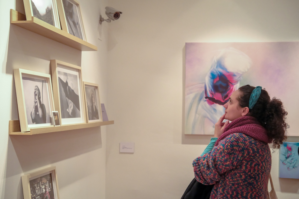 Una donna in un maglione colorato osserva opere d'arte esposte in una galleria.