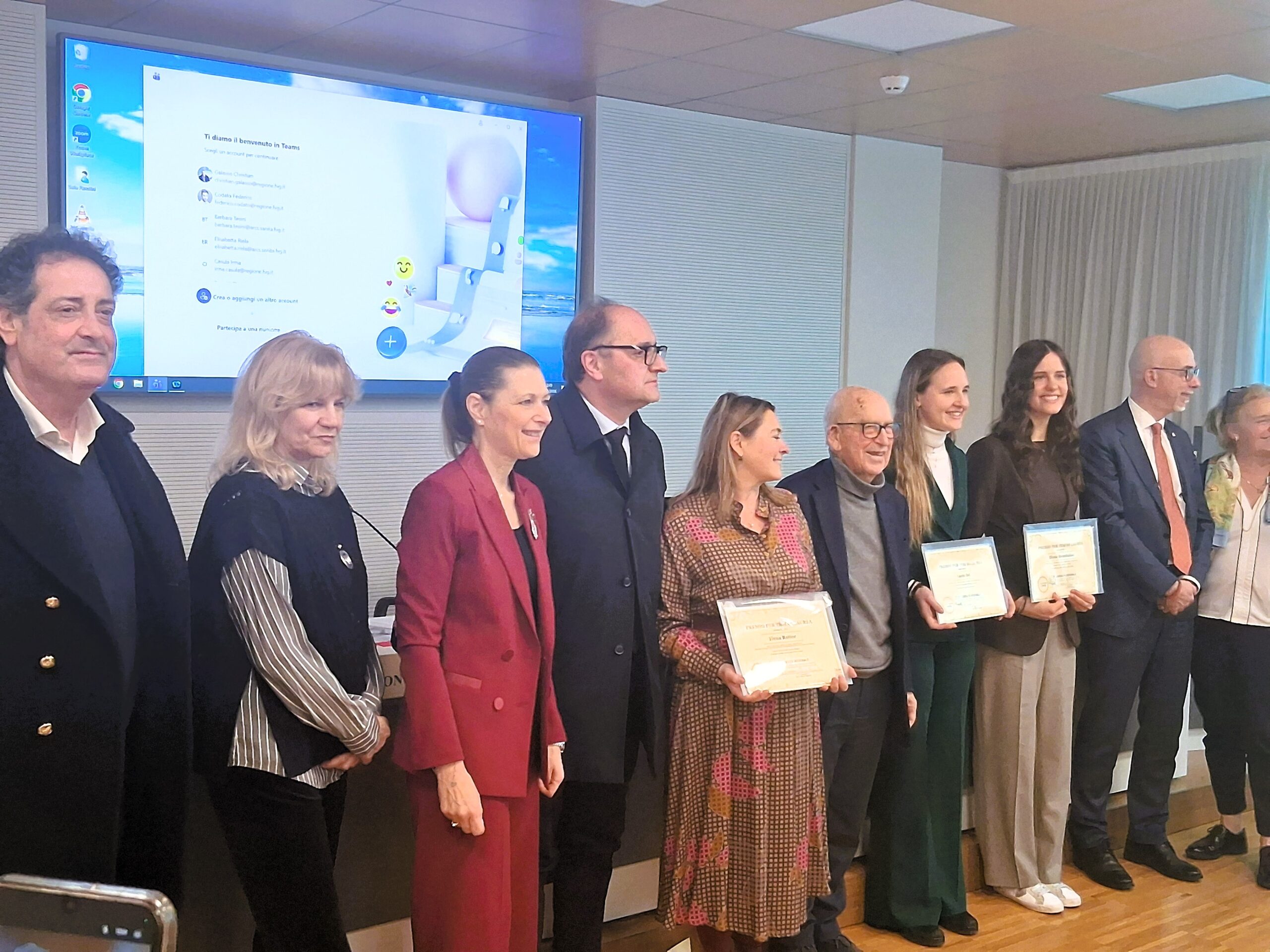 Gruppo di persone in piedi durante una cerimonia di premiazione in una sala conferenze
