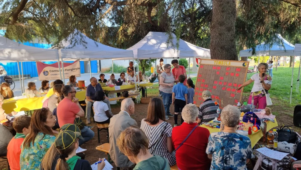 Festa di San Domenico 2026: il pubblico segue la tombola finale animata da Catine sotto i pini del quartiere.