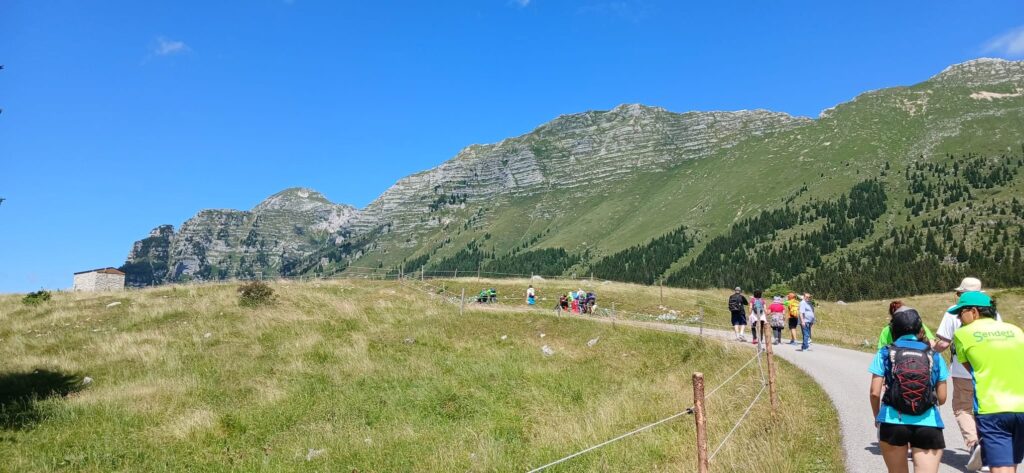 Il gruppo in cammino verso la malga sull'Altopiano del Montasio, sotto un cielo azzurro