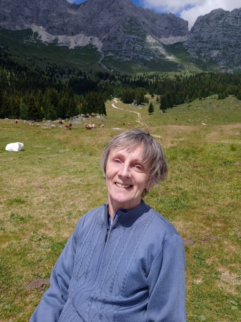 Partecipante sorridente sui prati del Montasio, con le mucche al pascolo e le montagne sullo sfondo