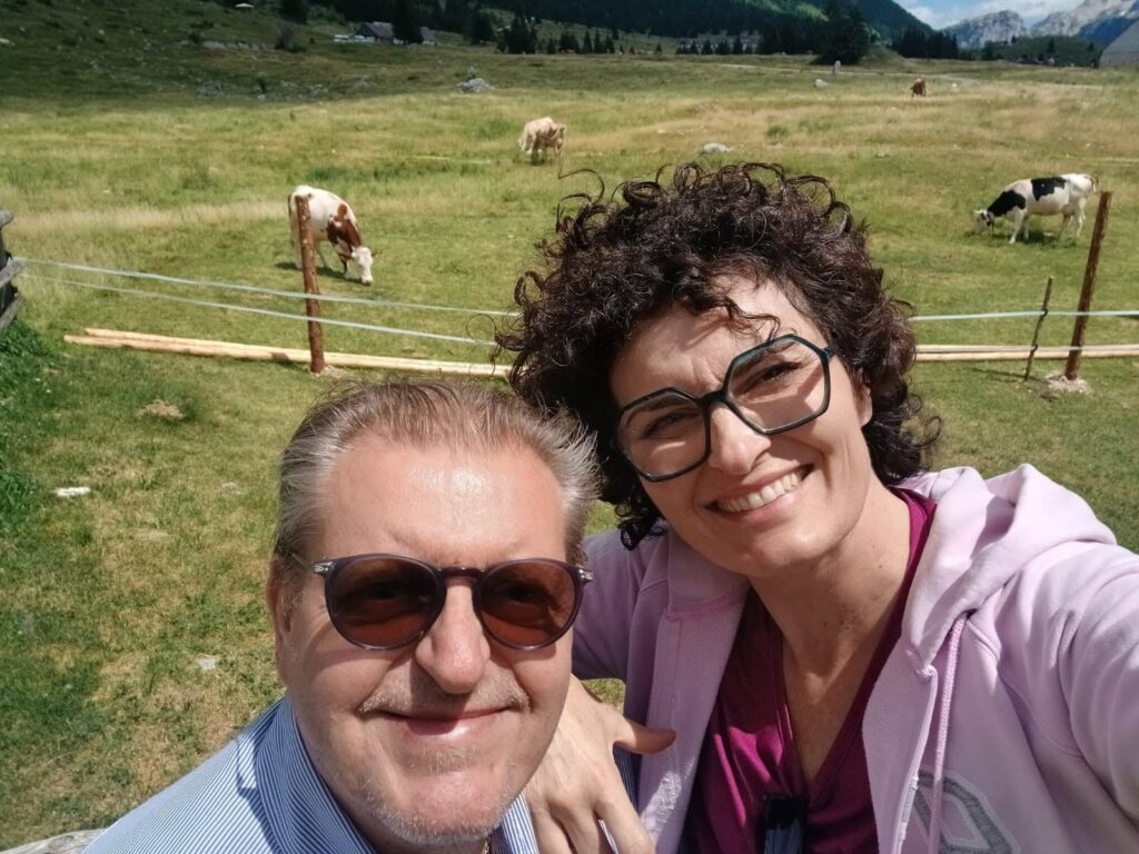 Selfie di due partecipanti davanti alle mucche al pascolo della Malga Montasio