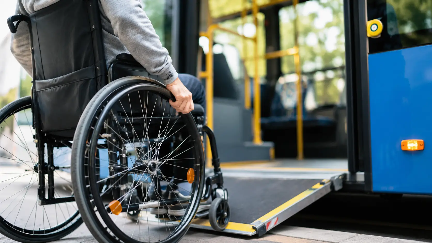 Persona in carrozzina sale su un autobus accessibile tramite rampa, in primo piano con sfondo sfocato.