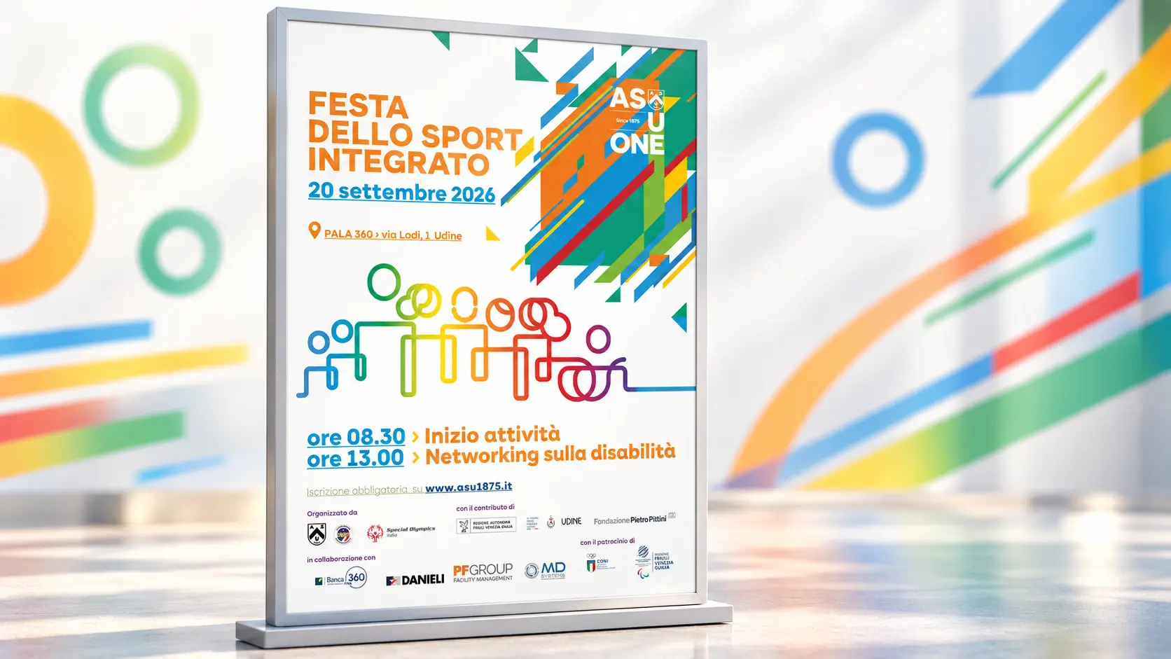 Locandina della Festa dello Sport Integrato del 20 settembre 2026, esposta su un supporto verticale in un ambiente luminoso e neutro con elementi grafici colorati sullo sfondo. In evidenza il titolo dell’evento, la sede Pala 360 di Udine e gli orari principali: inizio attività alle 8.30 e networking sulla disabilità alle 13.00.